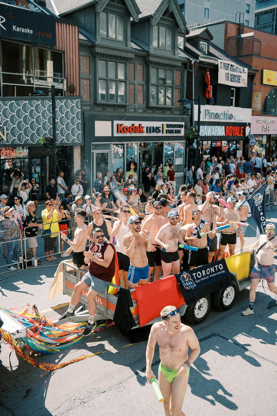 Participants from the Toronto Gay Hockey Association celebrate in a vibrant parade, surrounded by cheering spectators.