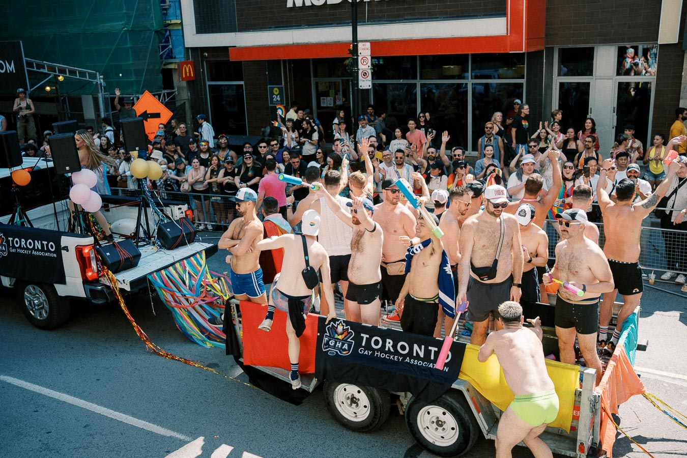 Participants on a parade float representing the Toronto Gay Hockey Association, celebrating with a lively crowd during a pride event.