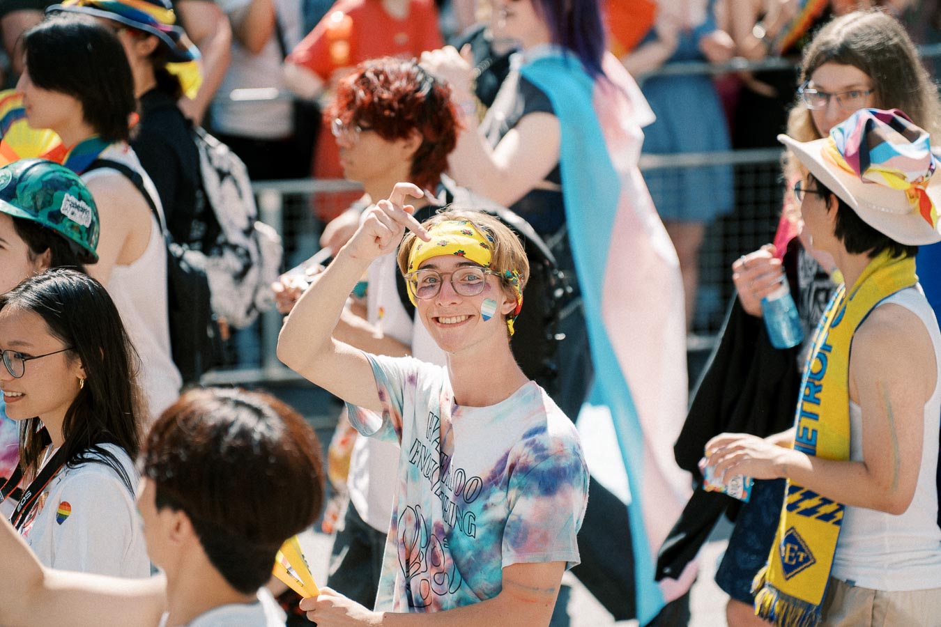 Participants celebrating at a pride parade, showcasing colorful attire and rainbow-themed accessories.