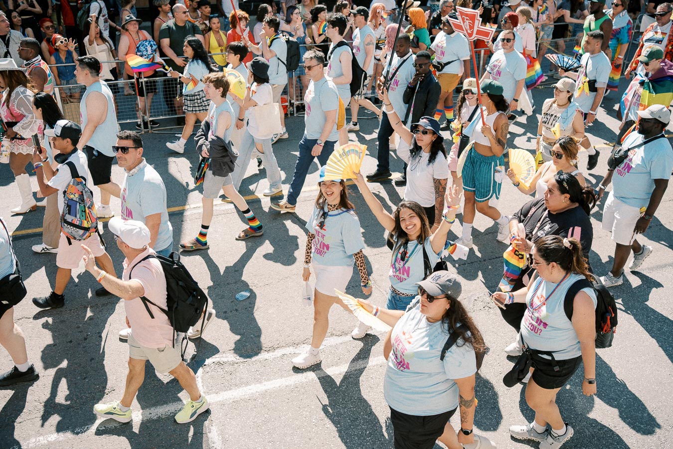 Participants joyfully march in a pride parade, showcasing vibrant outfits and rainbow flags, celebrating diversity and inclusion.