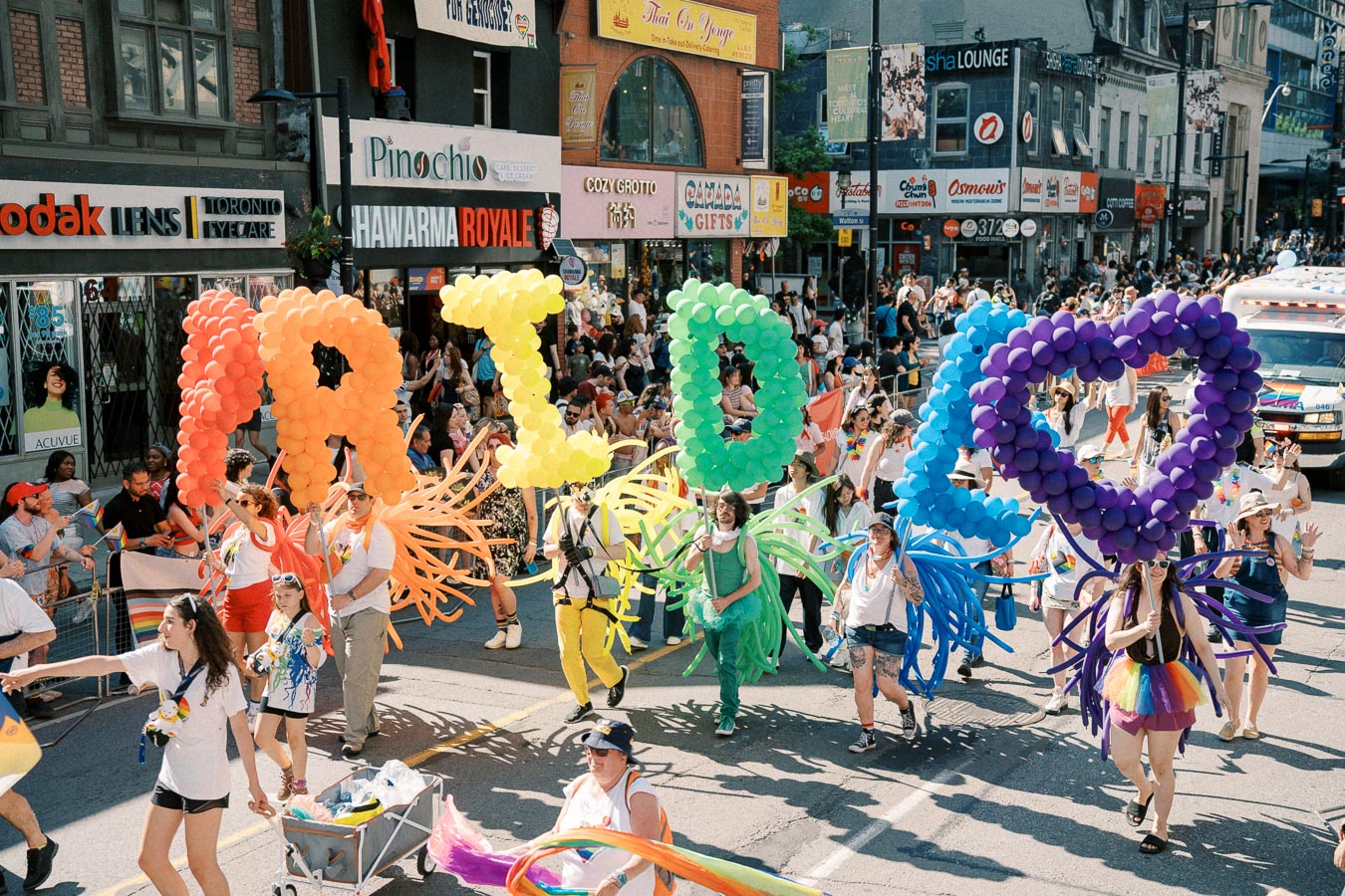 Participants in a pride parade hold colorful balloon letters spelling 'PRIDE', celebrating diversity and inclusion.