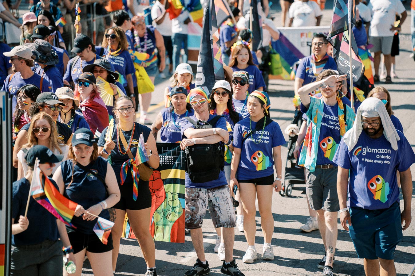 Participants in a pride parade wearing purple shirts with rainbow designs, celebrating diversity and inclusion.