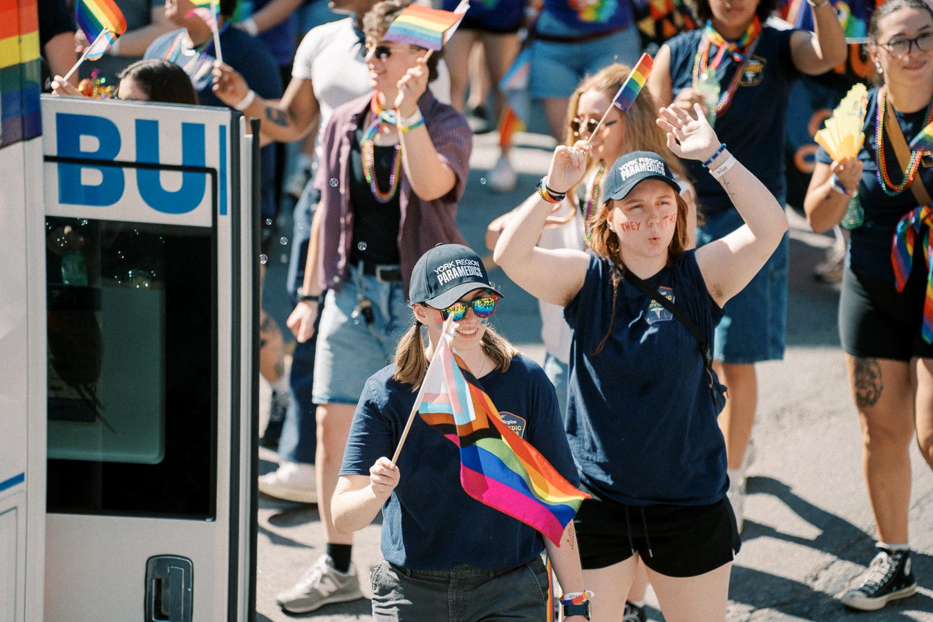 Participants in a pride parade celebrate with rainbow flags and vibrant attire, showcasing support for the LGBTQ+ community.