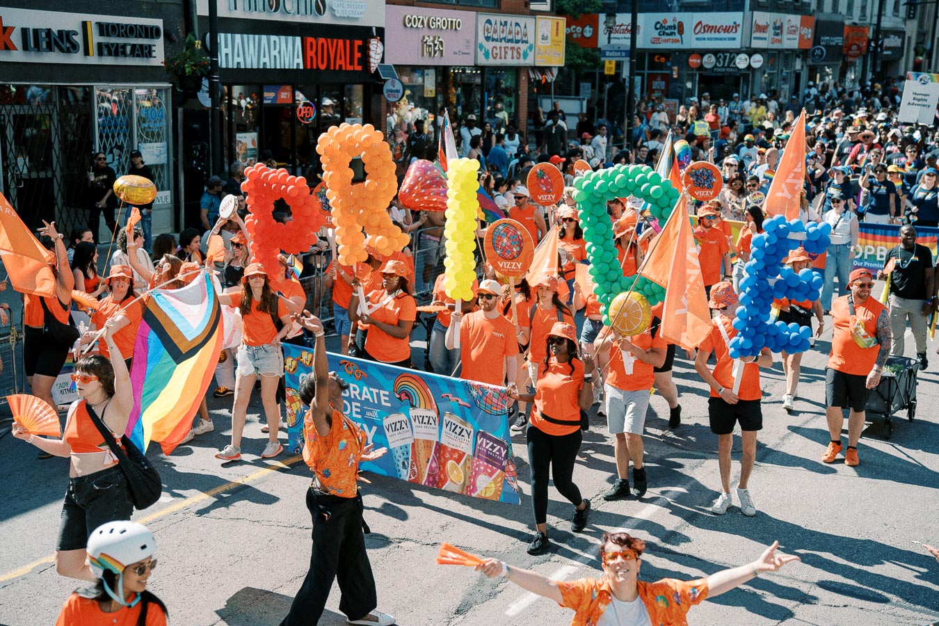 Participants in a Pride parade hold colorful balloon letters spelling 'PRIDE', celebrating diversity and inclusion.