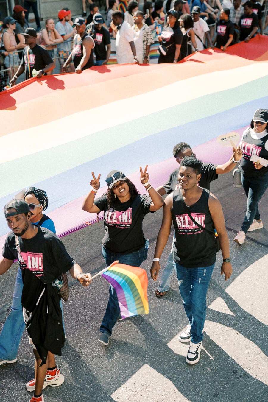 Participants in a pride parade carry a large rainbow flag, celebrating diversity and inclusion.
