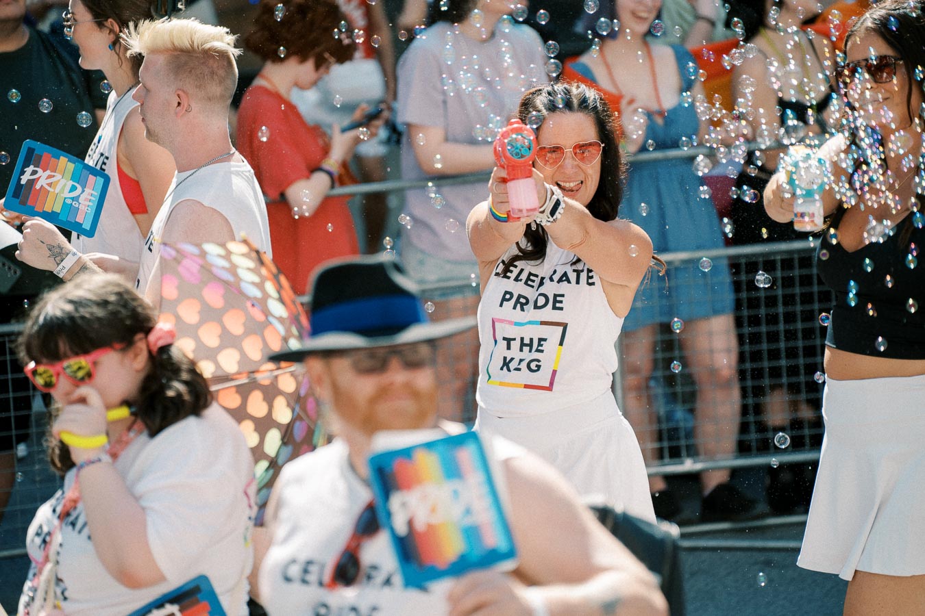Participants at a Pride parade joyfully celebrate with bubbles and colorful attire, embodying the spirit of inclusivity and diversity.