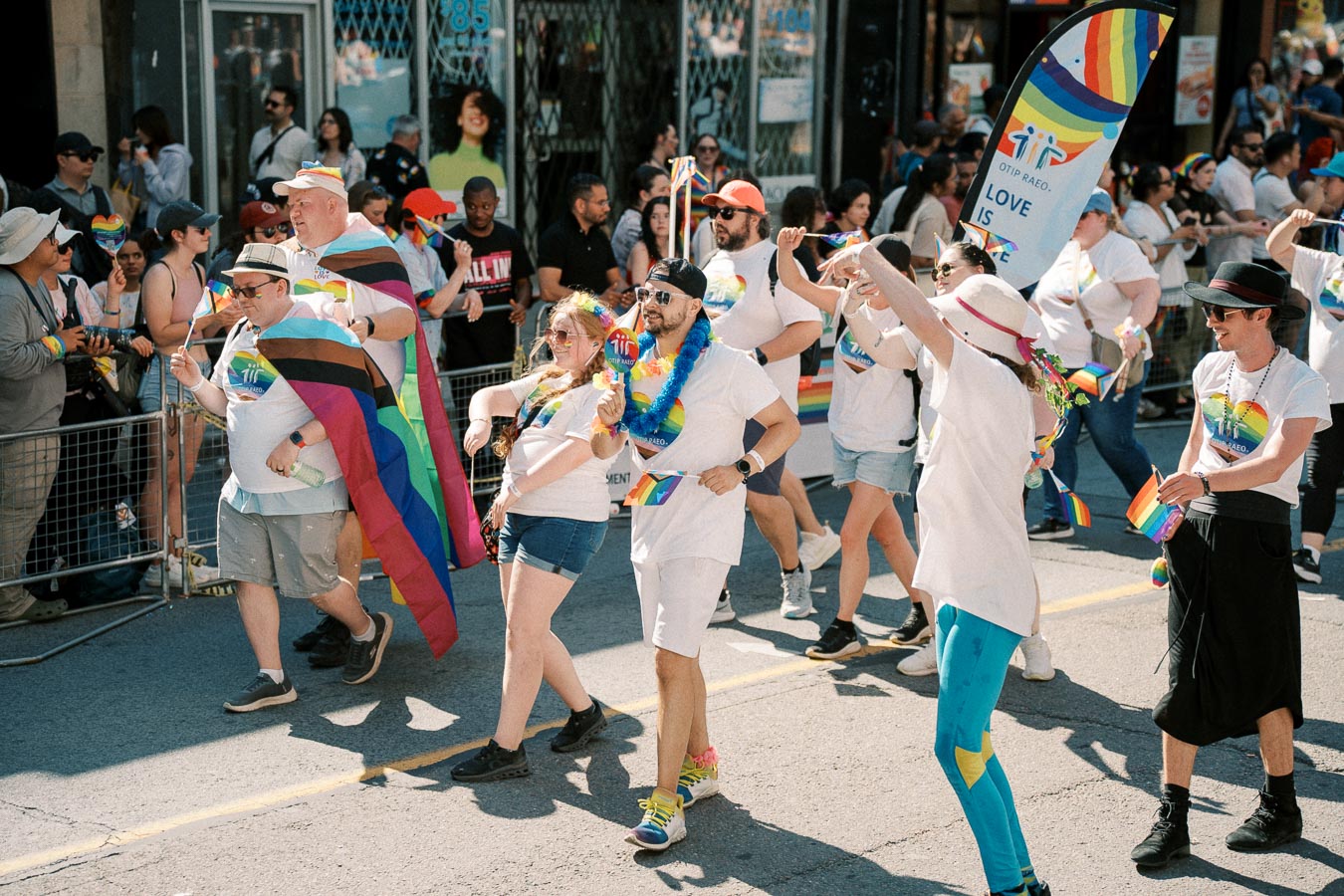 Participants in a pride parade celebrate with colorful flags and outfits, promoting love and inclusivity.