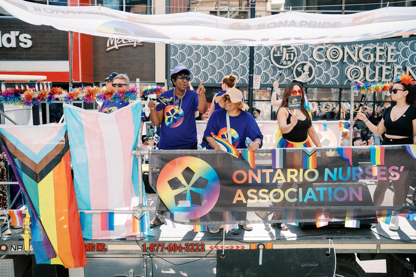 Participants from the Ontario Nurses' Association celebrate at a pride parade, showcasing rainbow and transgender flags.