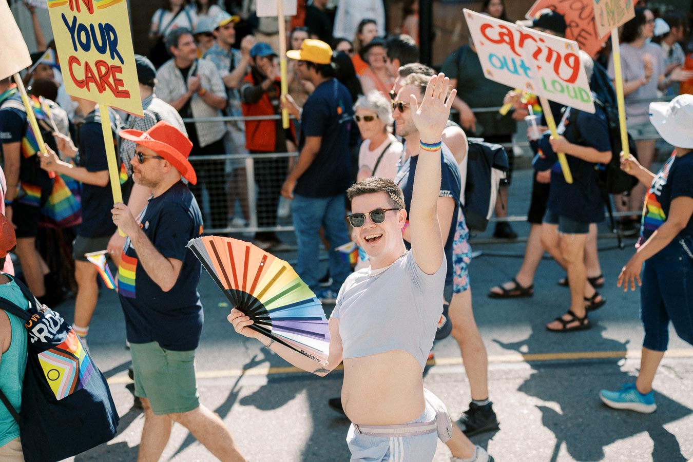 Participants in a vibrant pride parade, waving rainbow flags and holding signs, celebrate diversity and inclusion.