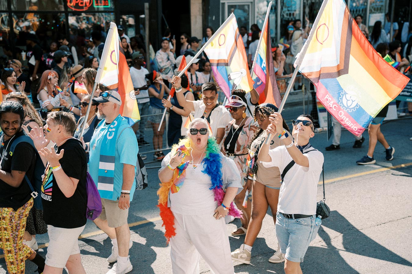 Participants in a pride parade celebrate with rainbow flags and vibrant attire, showcasing diversity and inclusion.
