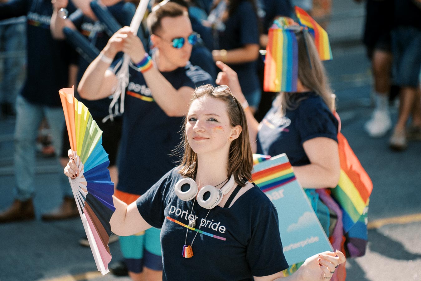 Participants at a pride parade celebrate with rainbow-themed accessories and attire, showcasing support for the LGBTQ+ community.