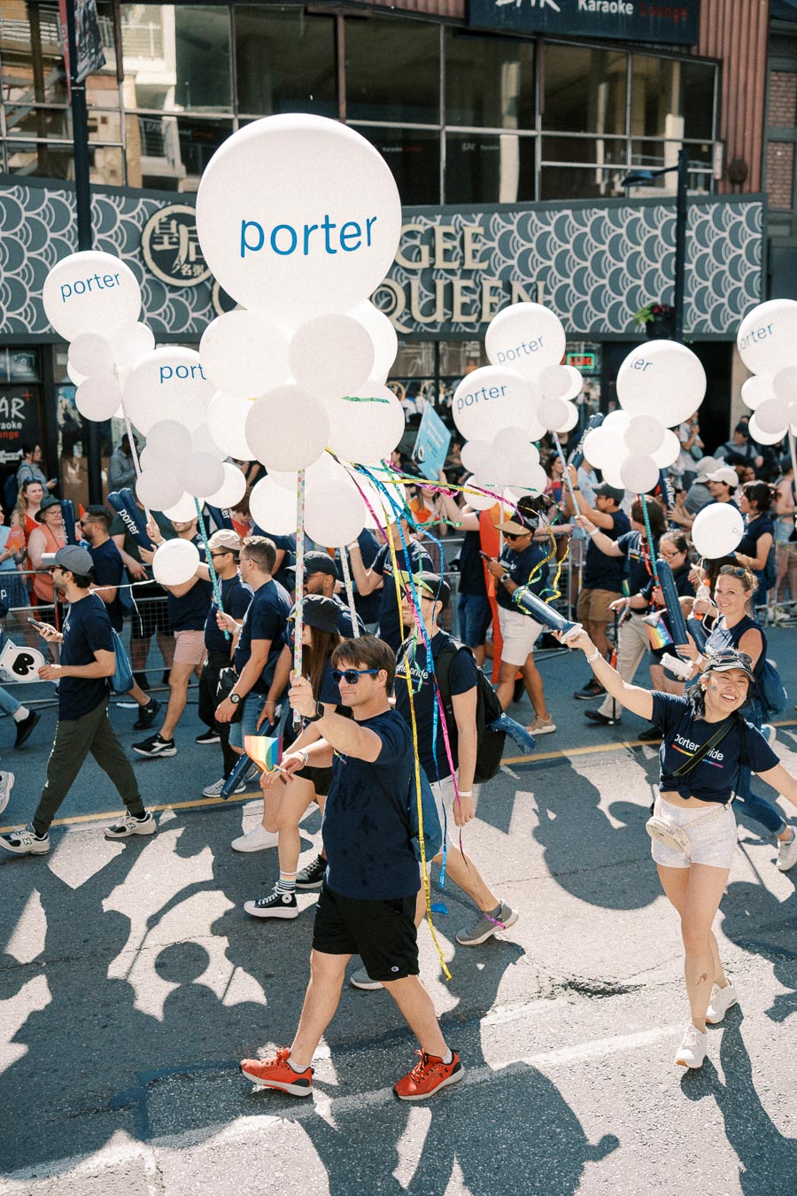 Participants in a parade hold white balloons with 'porter' written on them, celebrating with colorful attire and accessories.
