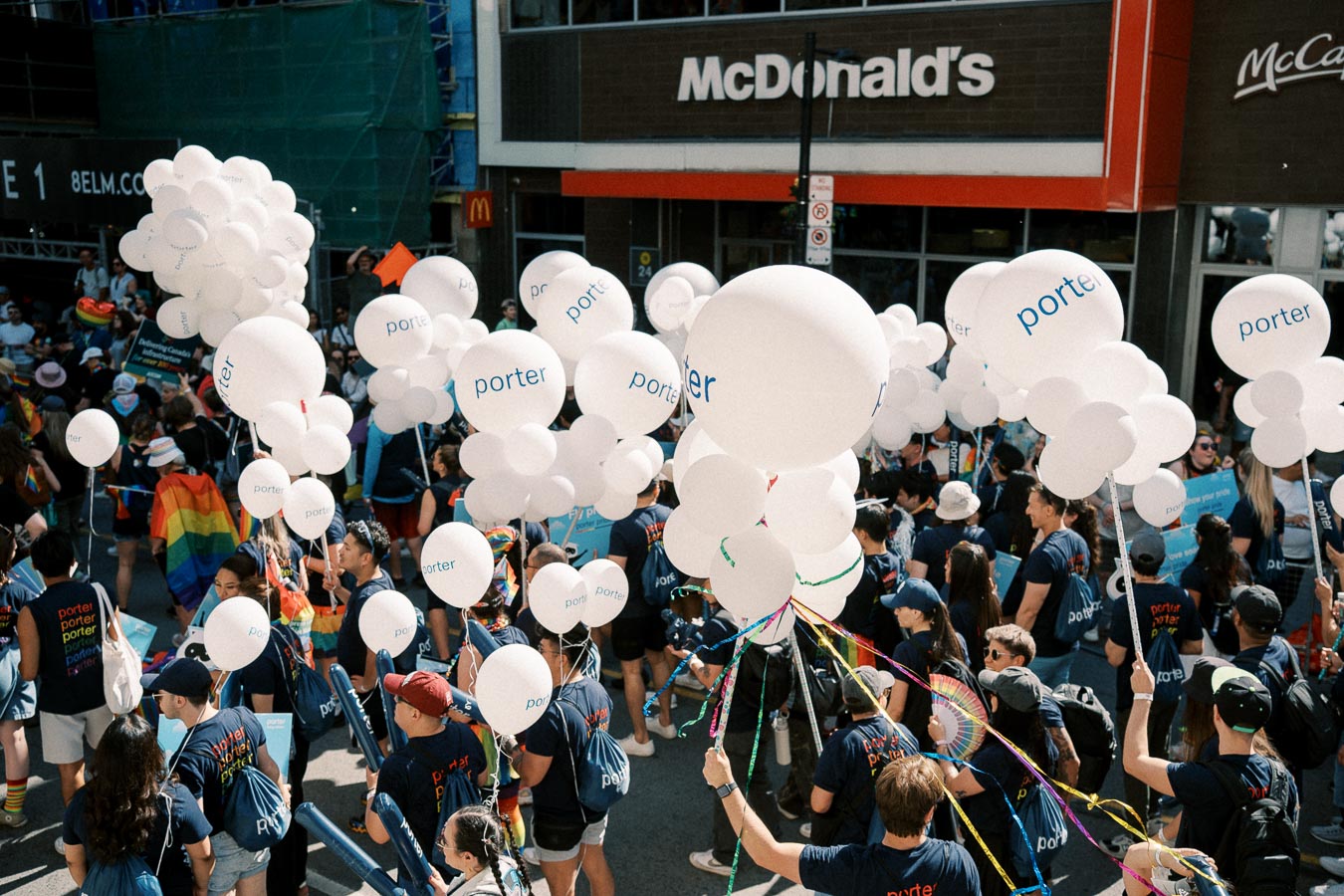 Participants in a parade hold 'porter' balloons near a McDonald's.