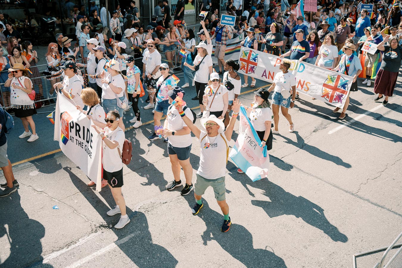 Participants in a pride parade march with banners and rainbow-themed attire, celebrating diversity and inclusion.