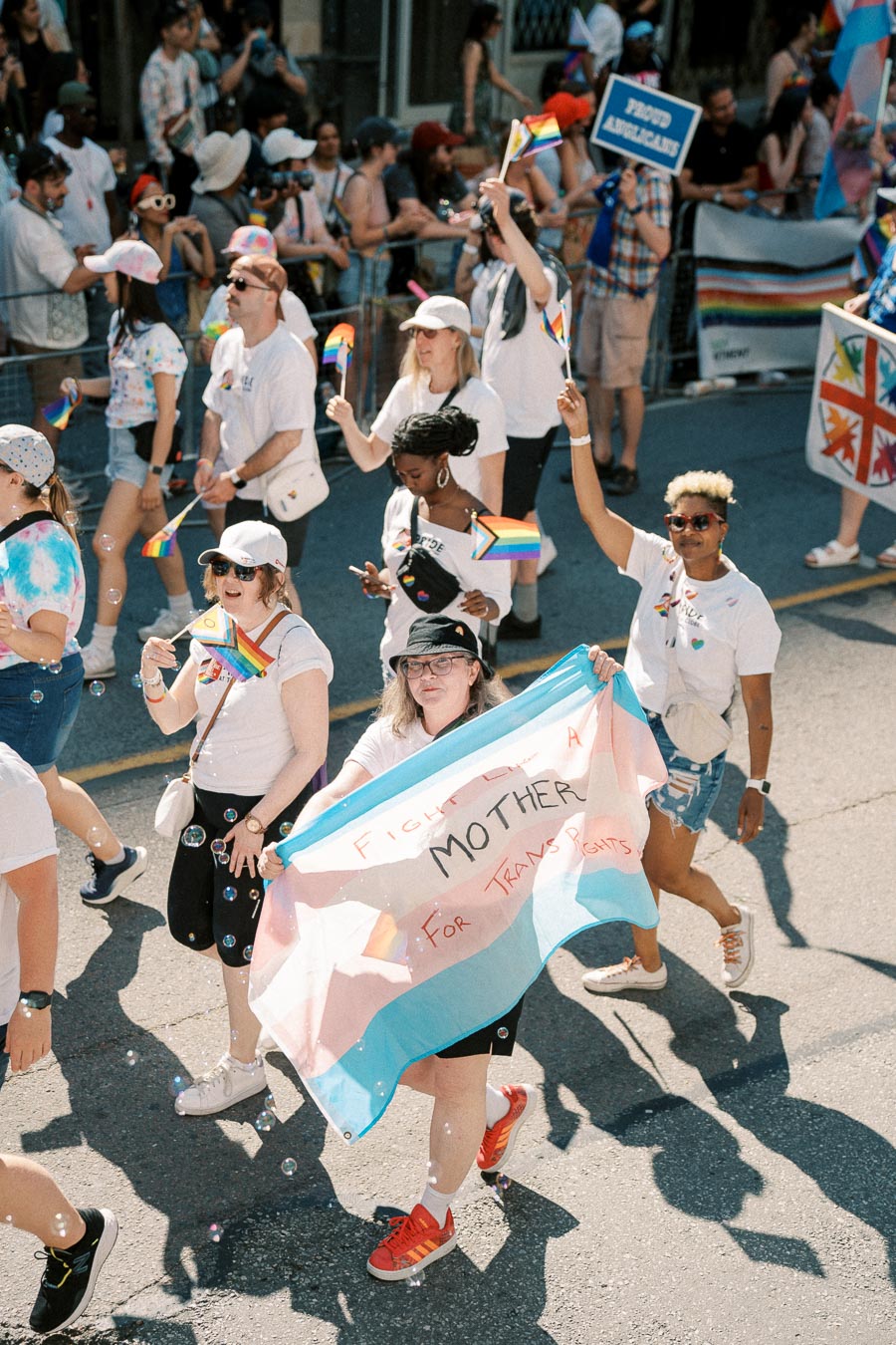 Participants at a pride parade hold rainbow flags and a banner advocating for trans rights.