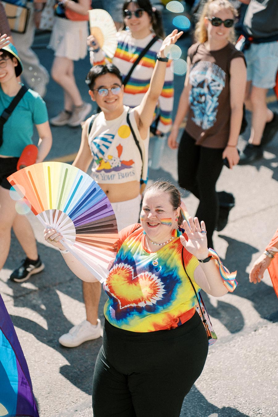 Participants joyfully celebrate at a pride parade, showcasing vibrant rainbow attire and accessories.