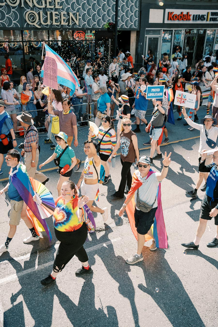 Participants in a pride parade celebrate diversity with colorful flags and signs.