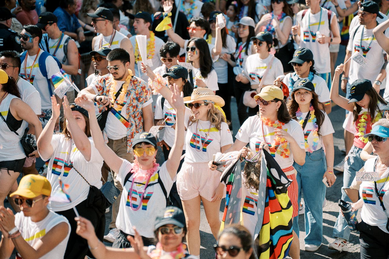 Participants in a pride parade wearing rainbow-themed attire and accessories, celebrating diversity and inclusion.