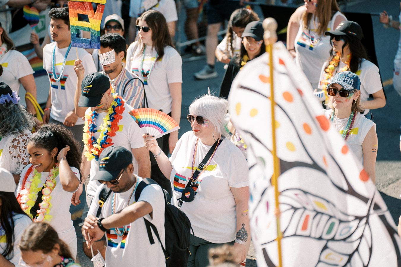 Participants in a pride parade celebrate with rainbow flags and colorful attire, showcasing support for the LGBTQ+ community.
