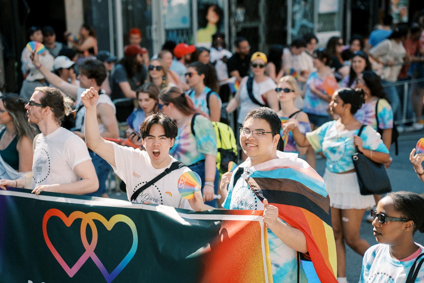Participants at a pride parade celebrate with colorful banners and attire, showcasing support for the LGBTQ+ community.