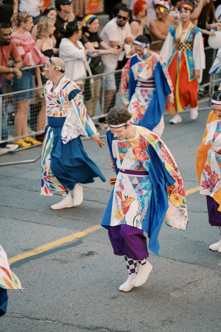 Performers in vibrant traditional Japanese attire participate in a lively parade, captivating the onlooking crowd.