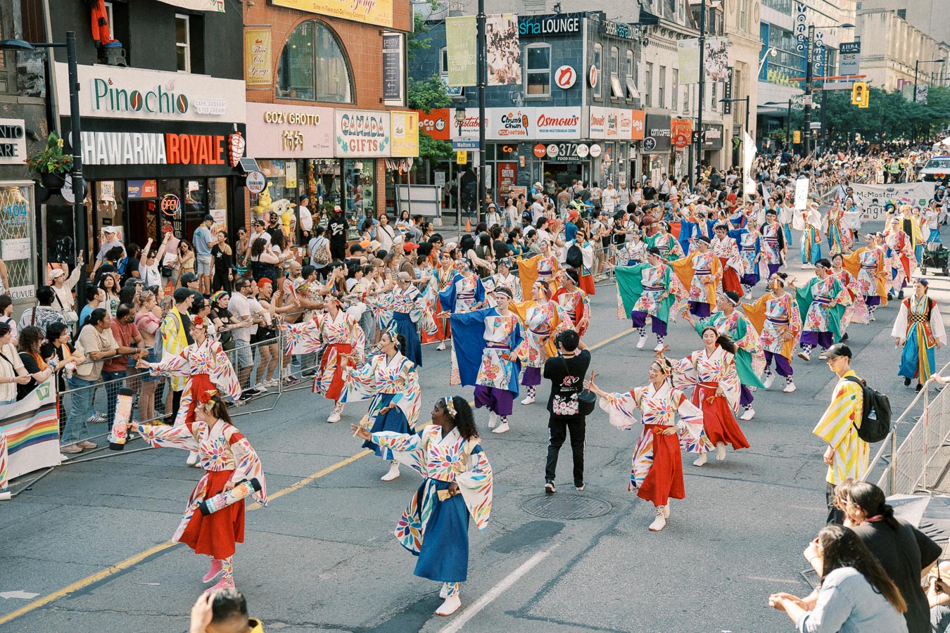 A lively street parade featuring dancers in colorful traditional costumes captivates a large crowd of spectators.