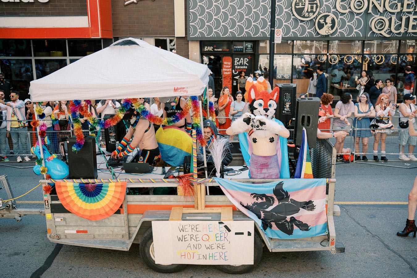 A vibrant float at a pride parade features individuals in colorful costumes and rainbow decorations, celebrating diversity and inclusion.