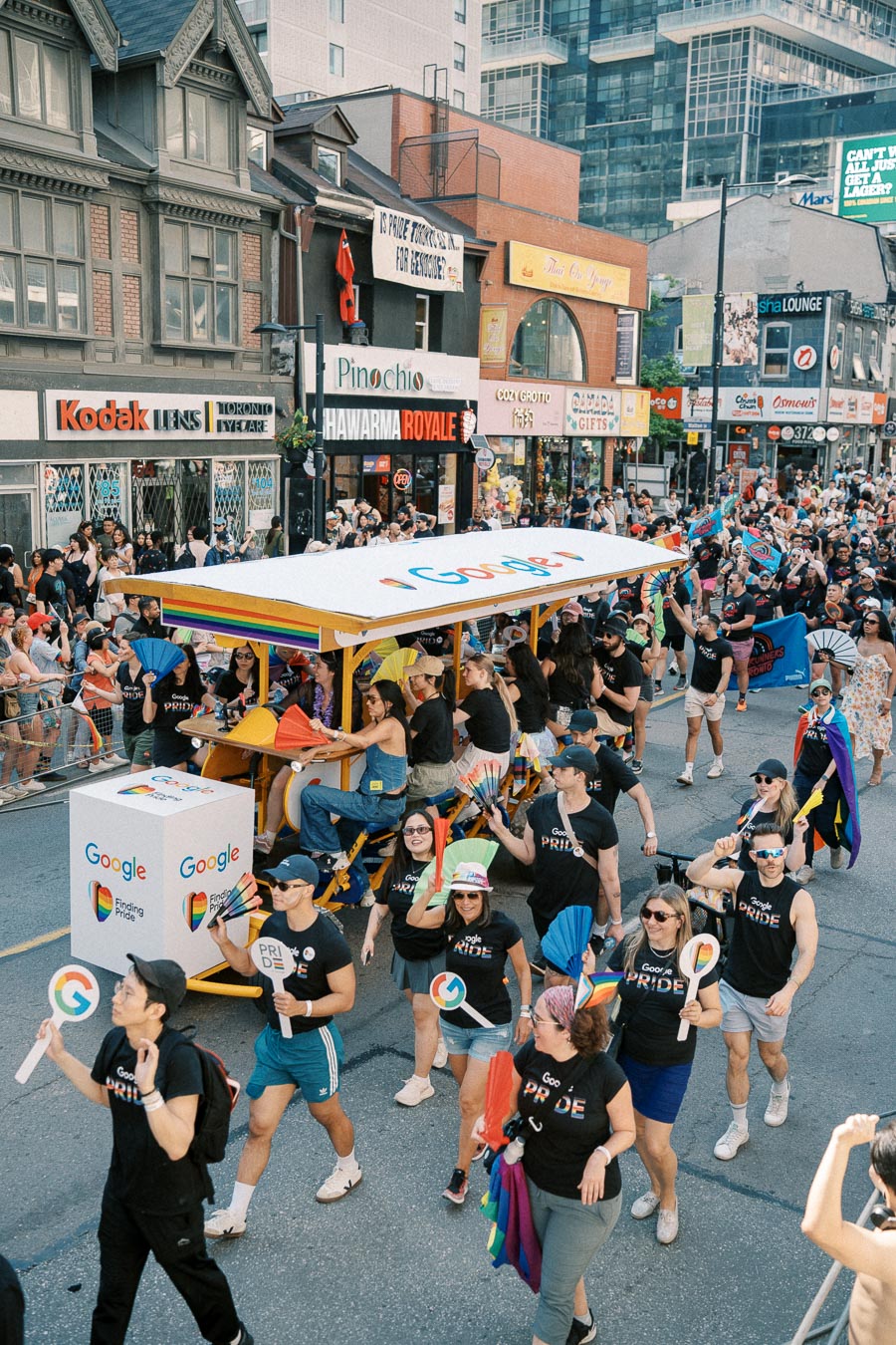 Participants in a Pride parade walk alongside a Google-branded float, celebrating diversity and inclusion.