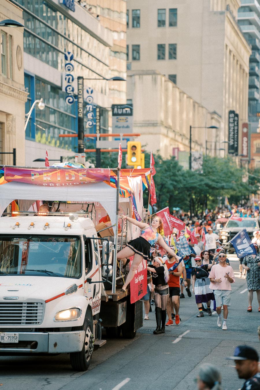 A lively pride parade featuring a decorated truck and participants in colorful attire, celebrating diversity on a city street.