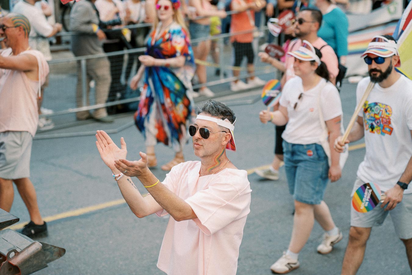 Participants in a pride parade celebrate with colorful attire and rainbow flags.