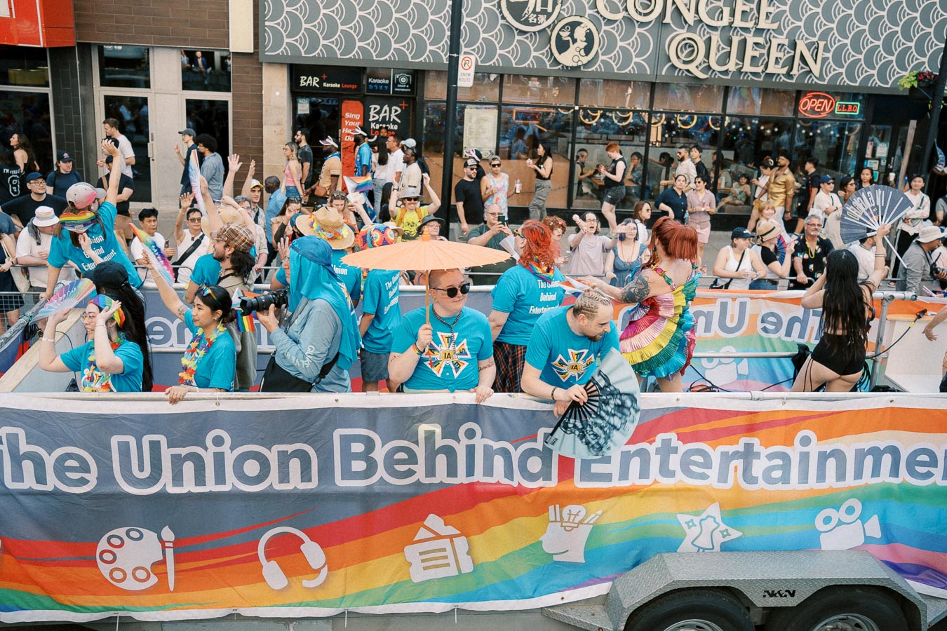 Participants in a parade hold a colorful banner reading 'The Union Behind Entertainment,' celebrating diversity and inclusion.
