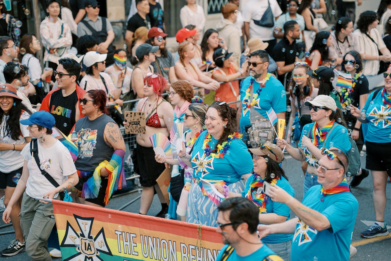 Participants in a vibrant pride parade, showcasing colorful attire and rainbow flags, celebrate diversity and inclusion.