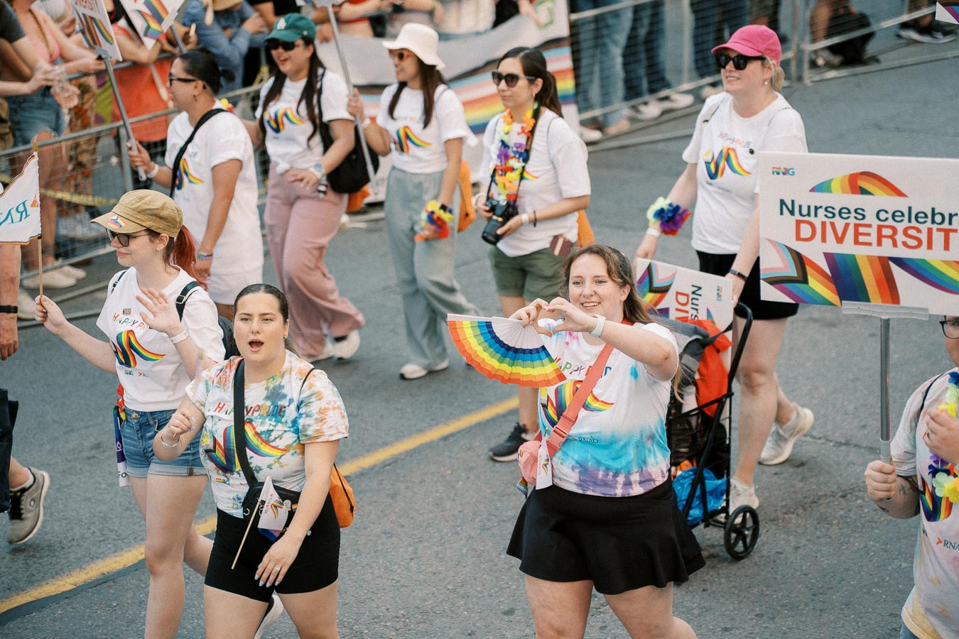 Participants in a pride parade celebrate diversity with rainbow-themed attire and signs.