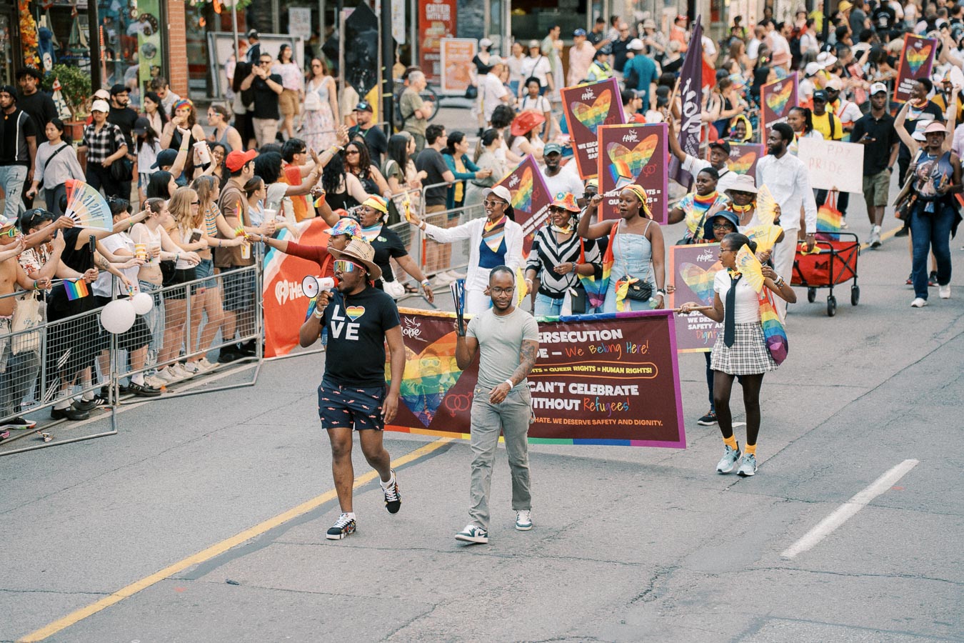 Participants in a pride parade march with colorful banners and rainbow flags, celebrating diversity and inclusion.