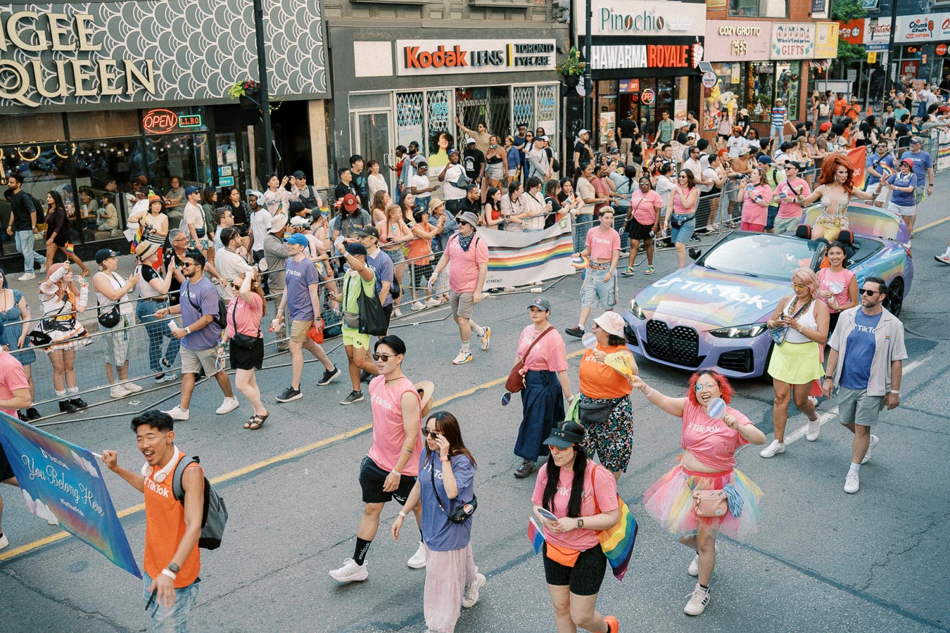 Participants in colorful attire march in a lively parade, celebrating diversity and inclusion, as spectators cheer from the sidelines.