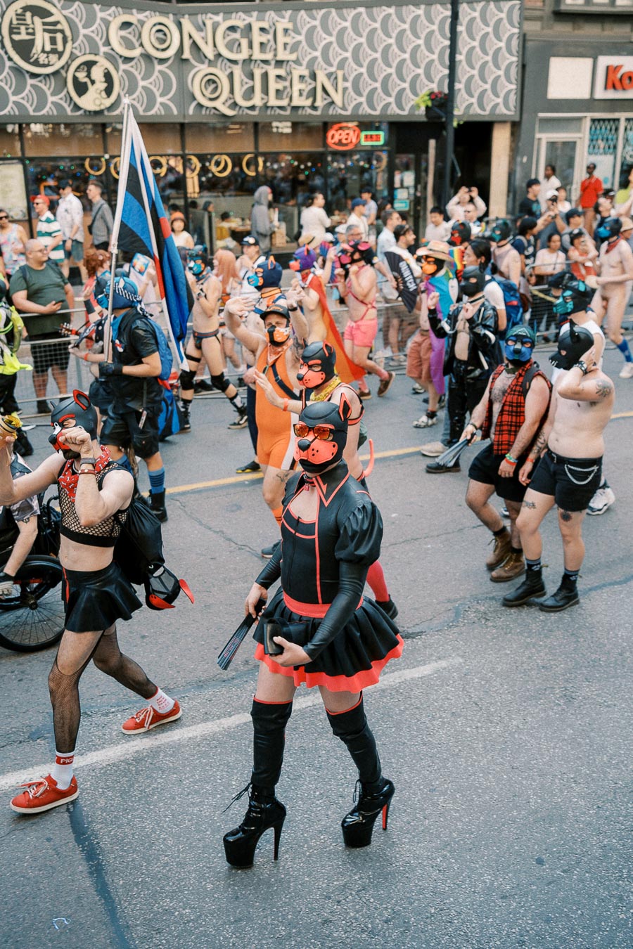 Participants in vibrant costumes march in a parade, showcasing diverse expressions of creativity and identity.