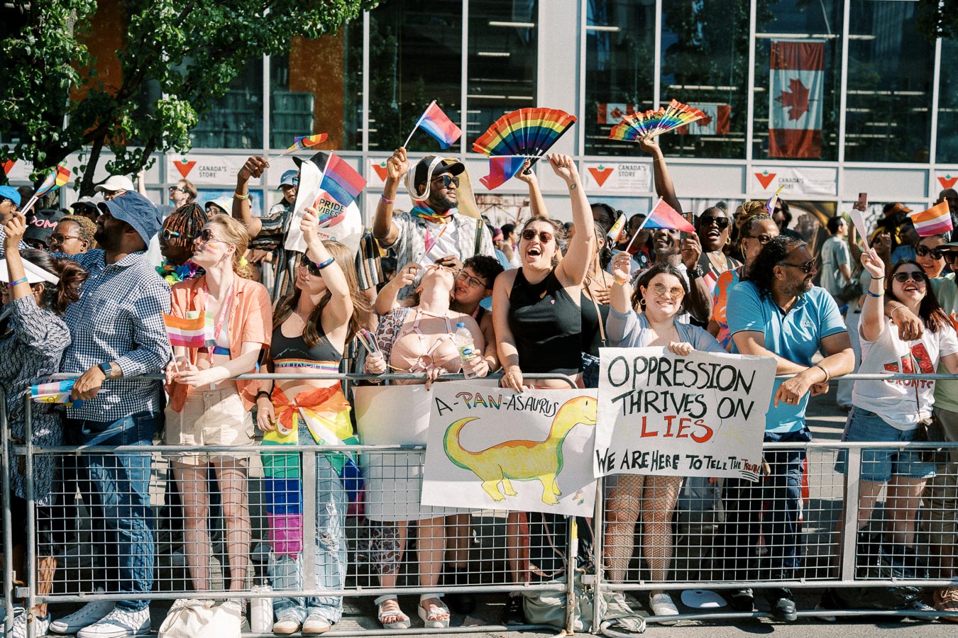 Participants at a pride parade celebrate with rainbow flags and signs, expressing messages of inclusivity and truth.