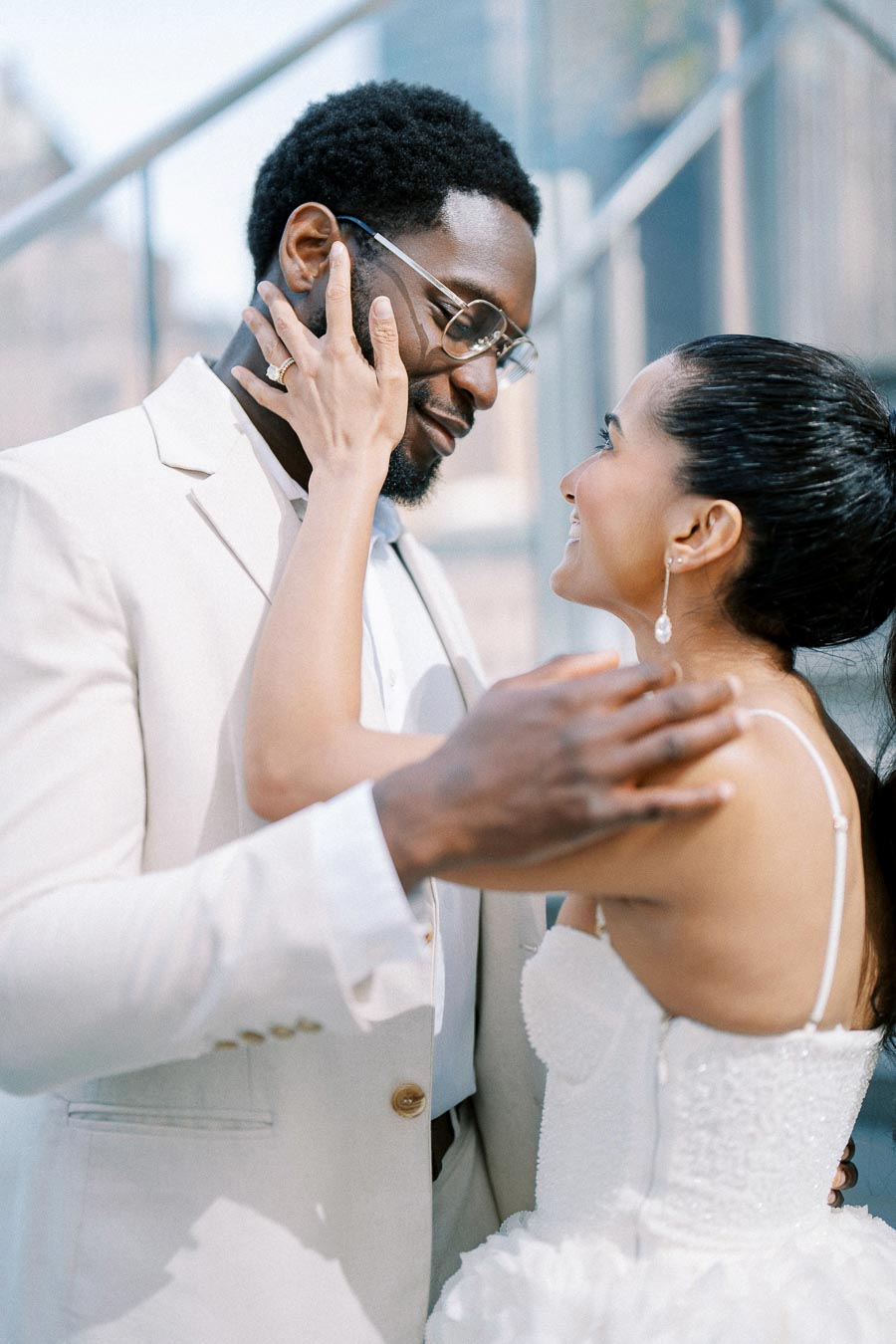 A joyful couple on their wedding day, dressed in elegant attire, share an intimate moment with smiles, symbolizing love and commitment.