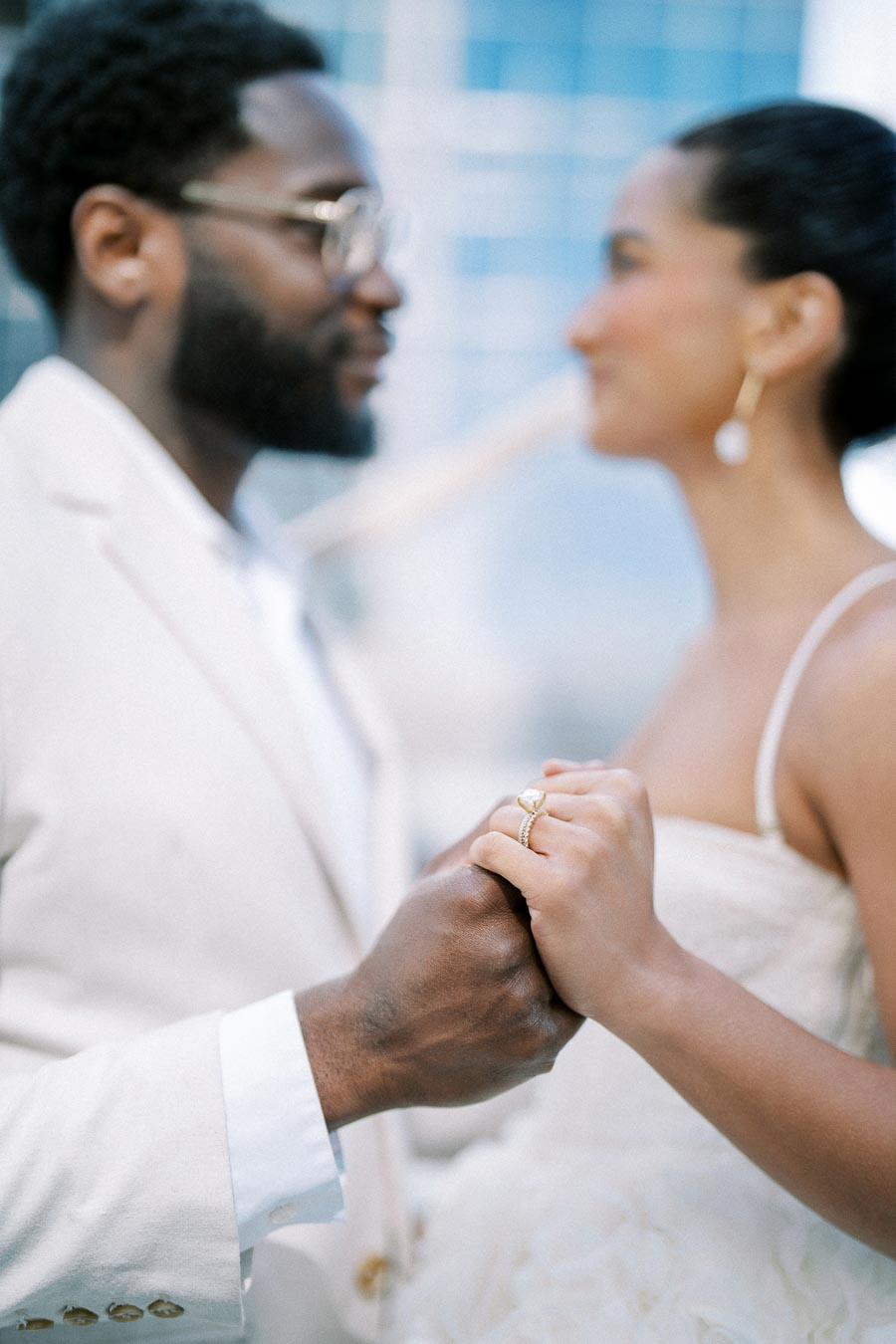 Stylish couple holding hands and gazing at each other, showcasing elegance and romance in formal attire