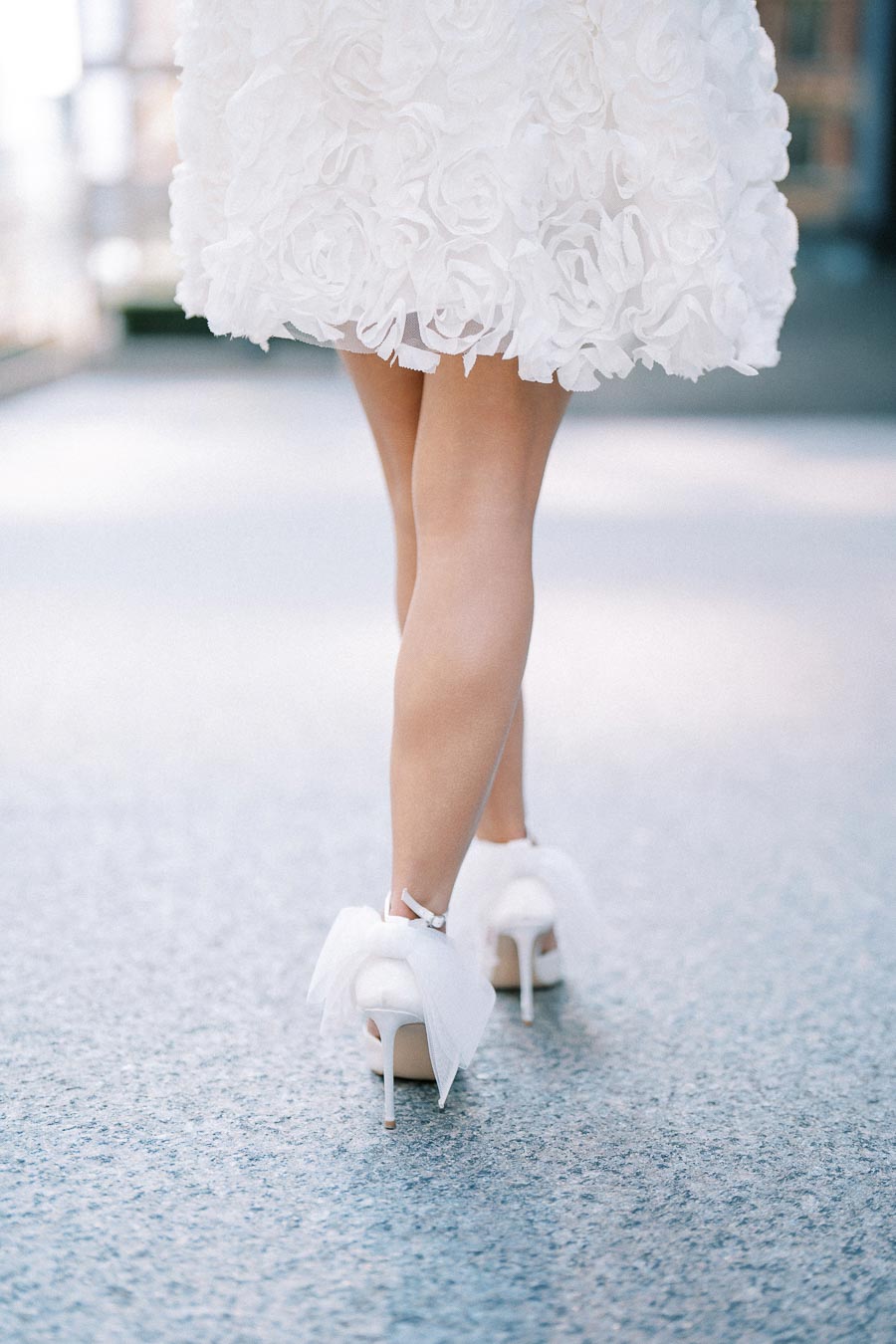 Elegant woman in a white floral dress walking in stylish high heels.