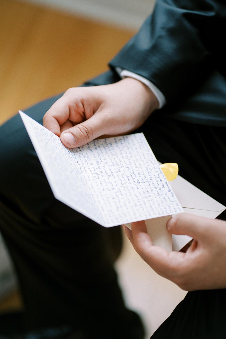 Man in a suit sits down and holds an open letter with handwritten text, emphasizing the importance of personal communication.
