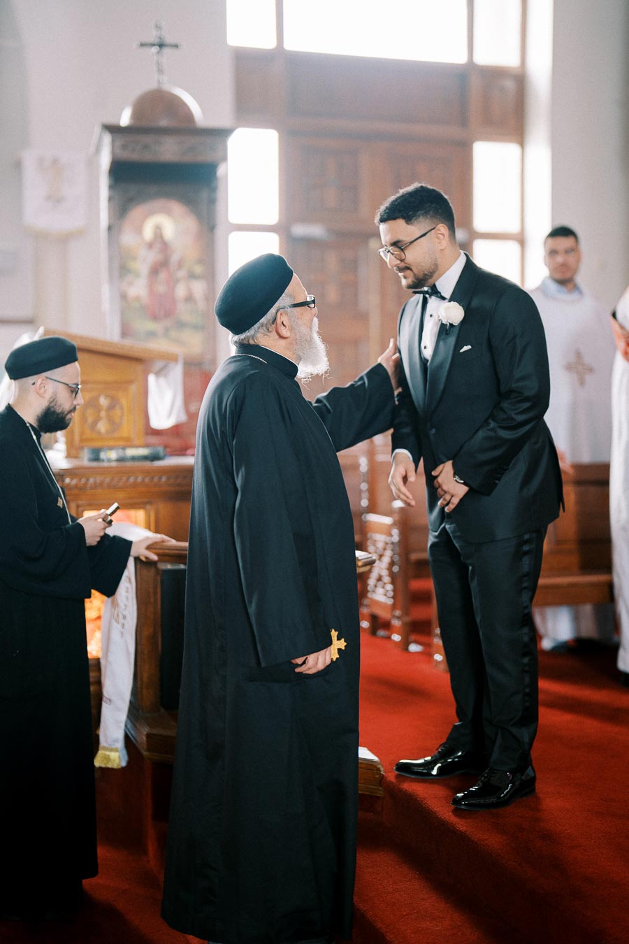 Clergyman blessing a groom in a traditional church ceremony, emphasizing religious customs.
