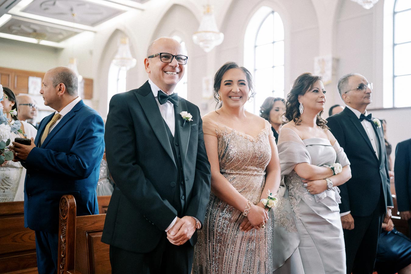 A joyful group dressed in formal attire attends a wedding ceremony inside an elegantly decorated church.