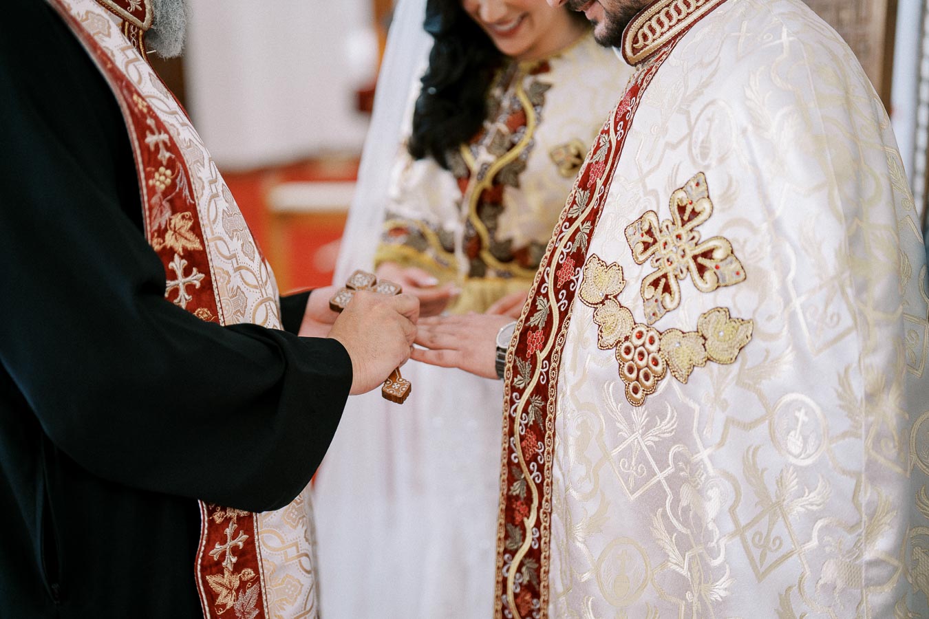 A priest performing a traditional wedding ceremony, blessing a couple in ornate robes and exchanging rings.