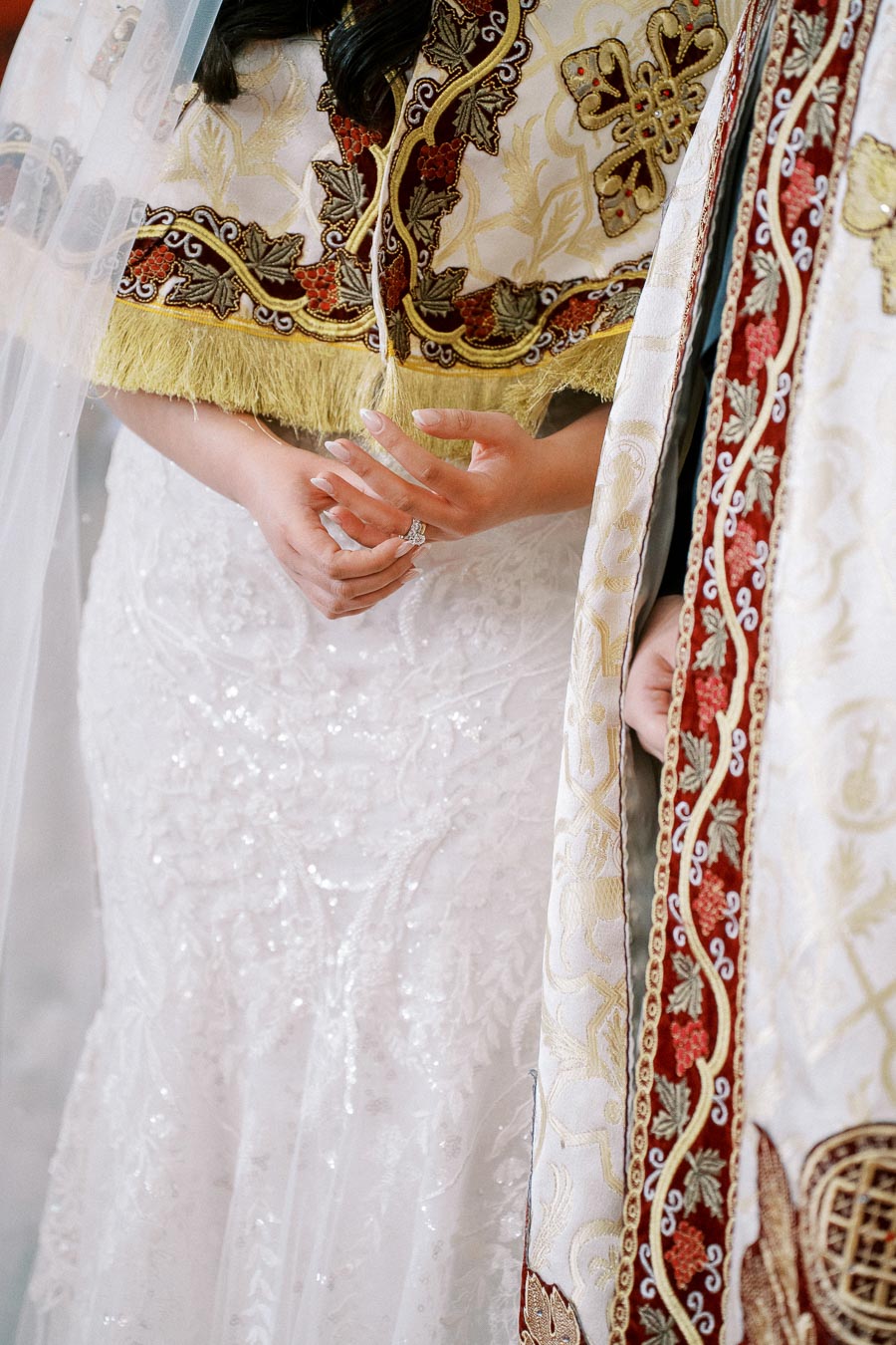 Bridal couple wearing intricately embroidered traditional attire during a wedding ceremony, featuring gold and red details.