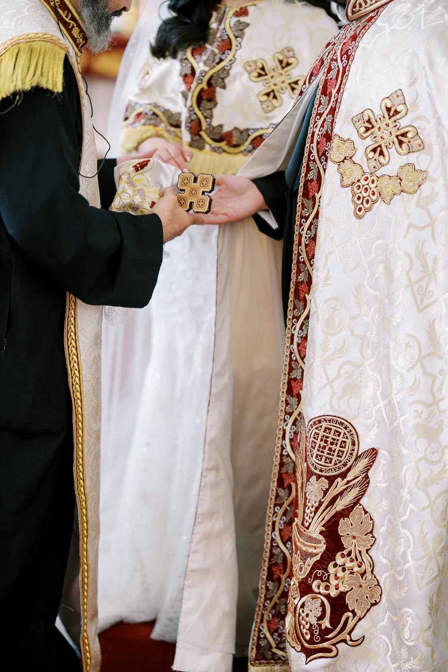 Priests wearing ornate liturgical vestments perform a religious ceremony, featuring intricate embroidered designs and symbolic patterns.