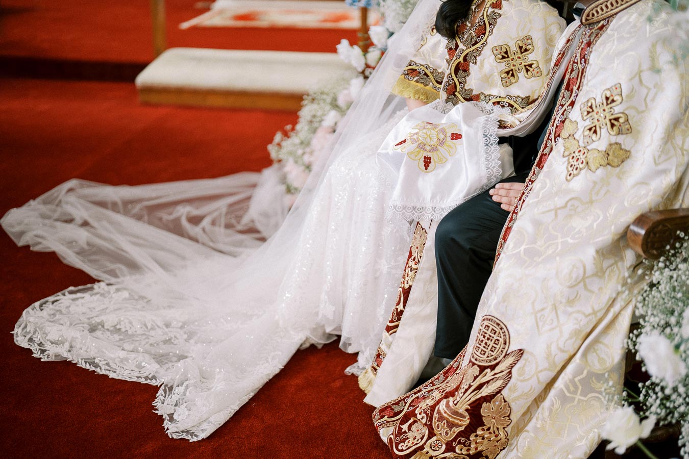 Elegant wedding attire with intricate embroidery and lace detailing on a red carpet, highlighting cultural and ceremonial richness.
