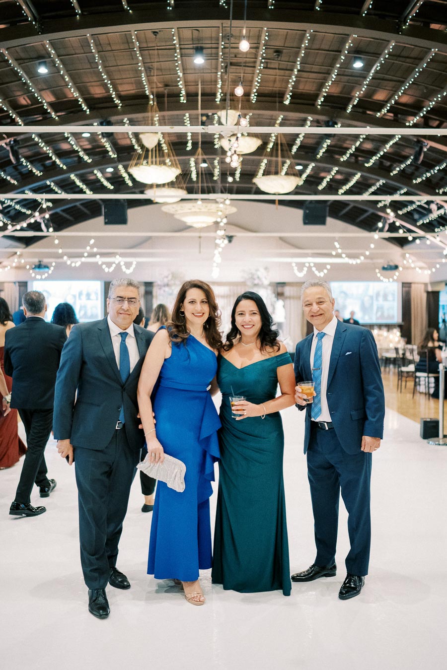 Elegant group of four people in formal attire at a glamorous indoor event, surrounded by sparkling ceiling lights and sophisticated decor.