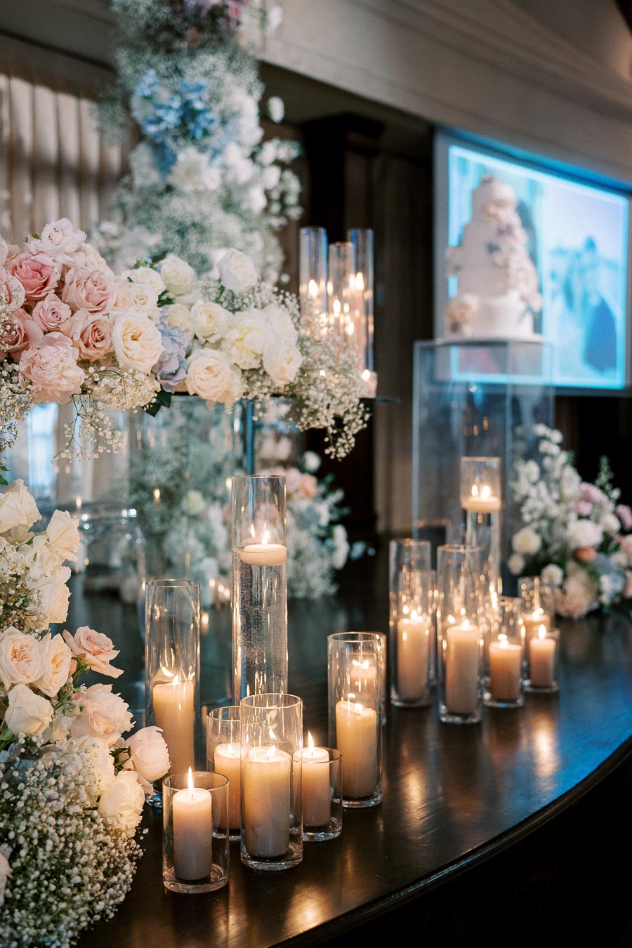 Elegant wedding reception with romantic candlelit table and floral arrangements featuring white and pink roses.
