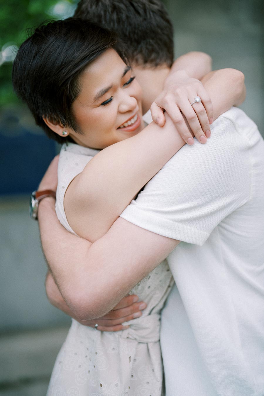 A smiling couple embraces lovingly, highlighting a sparkling engagement ring on the woman's hand.
